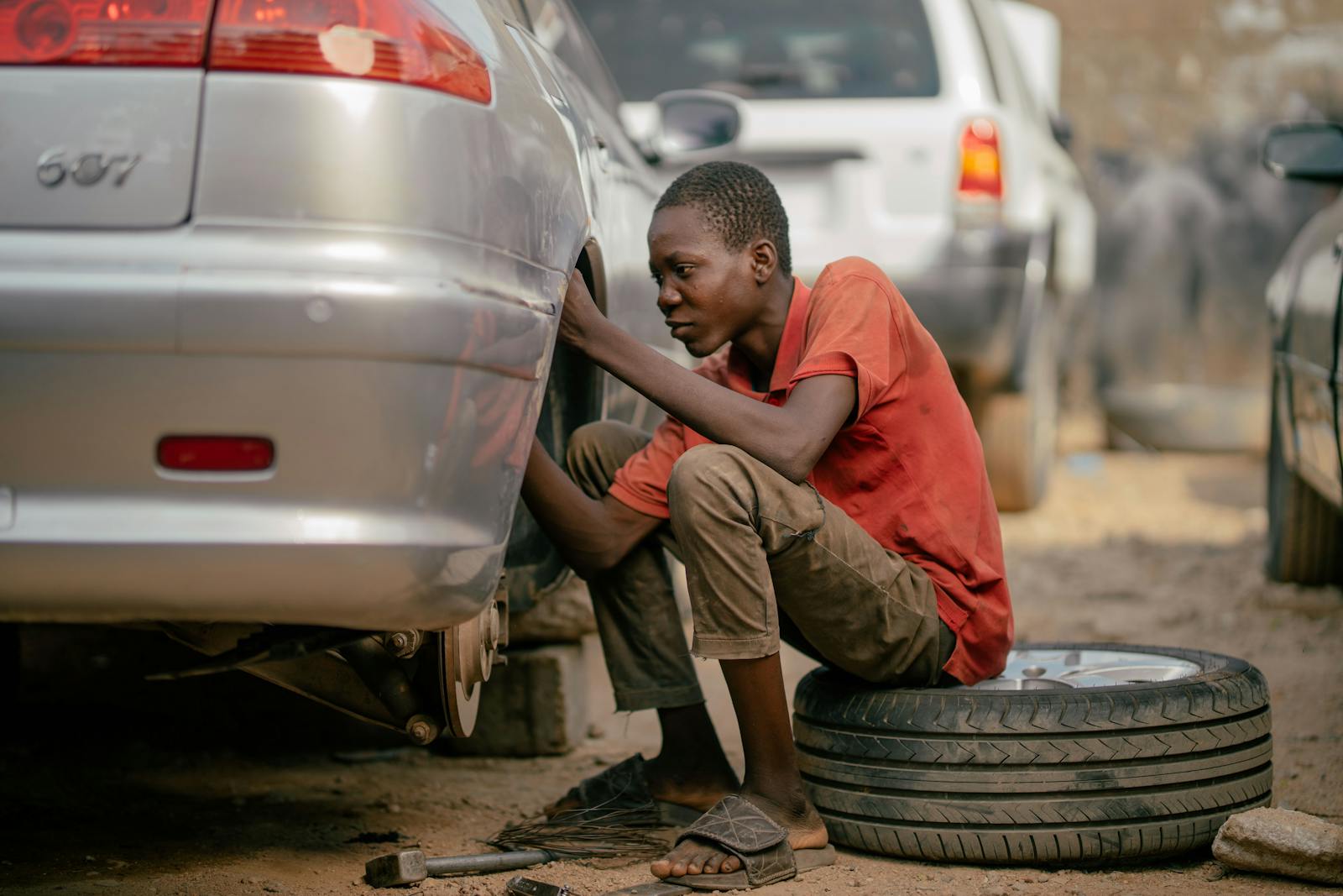 Outdoor tire change with tools laid out on pavement — side hustle mechanic work